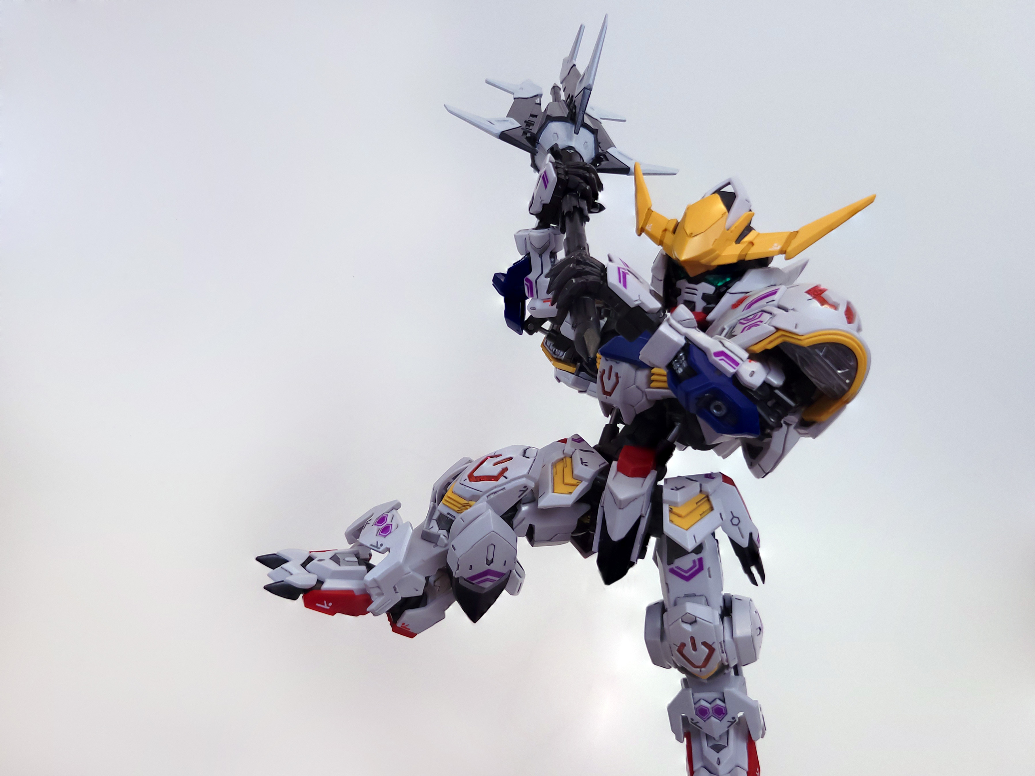 Barbatos stands on one foot, its other raised along with the massive mace in its arms: the machine is preparing to swing the mace overhand at the viewer