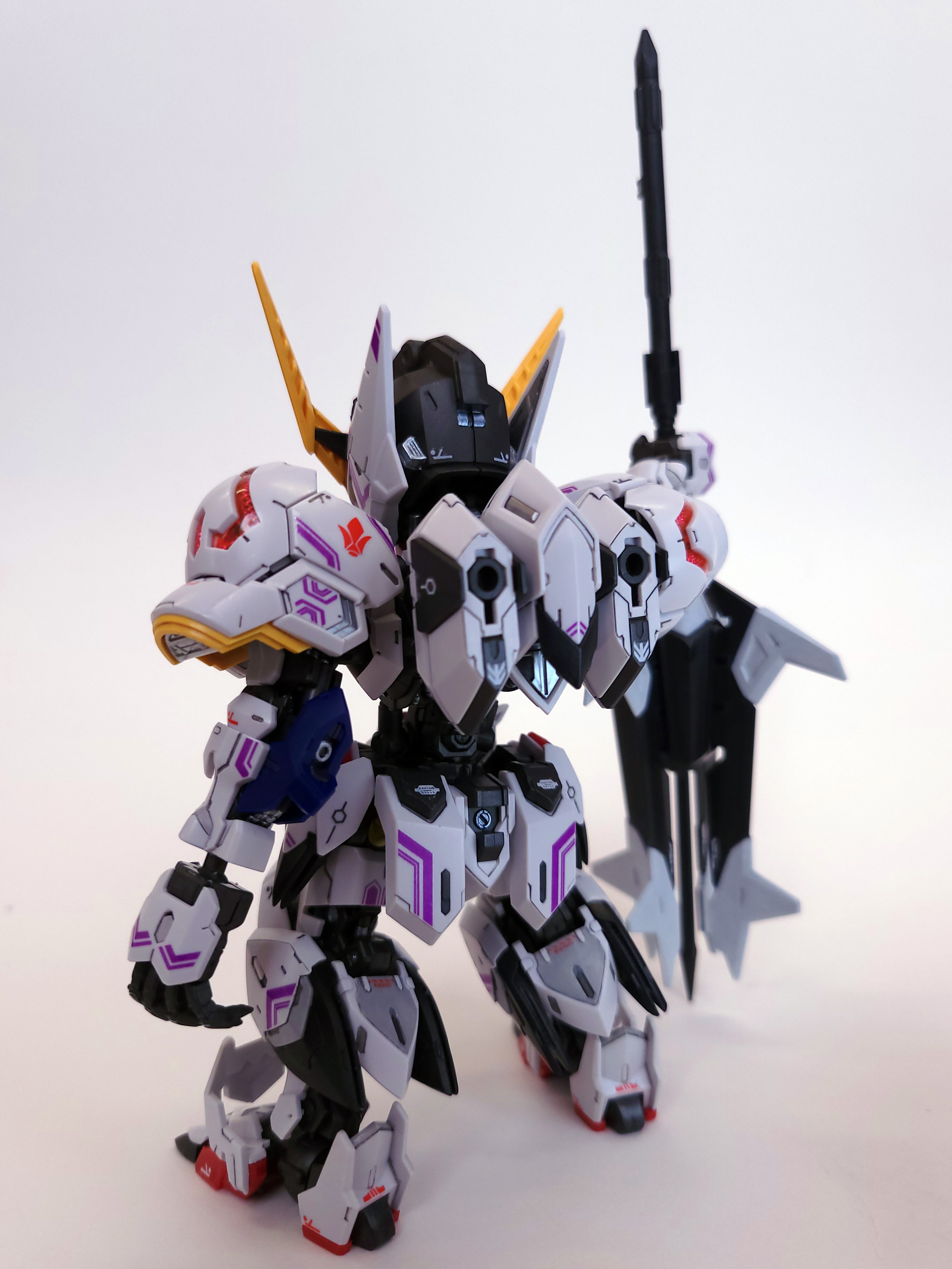 Another view of MGSD Barbatos from the back. It is holding a massive mace planted in the ground next to it. The mace is nearly as large as the mobile suit.