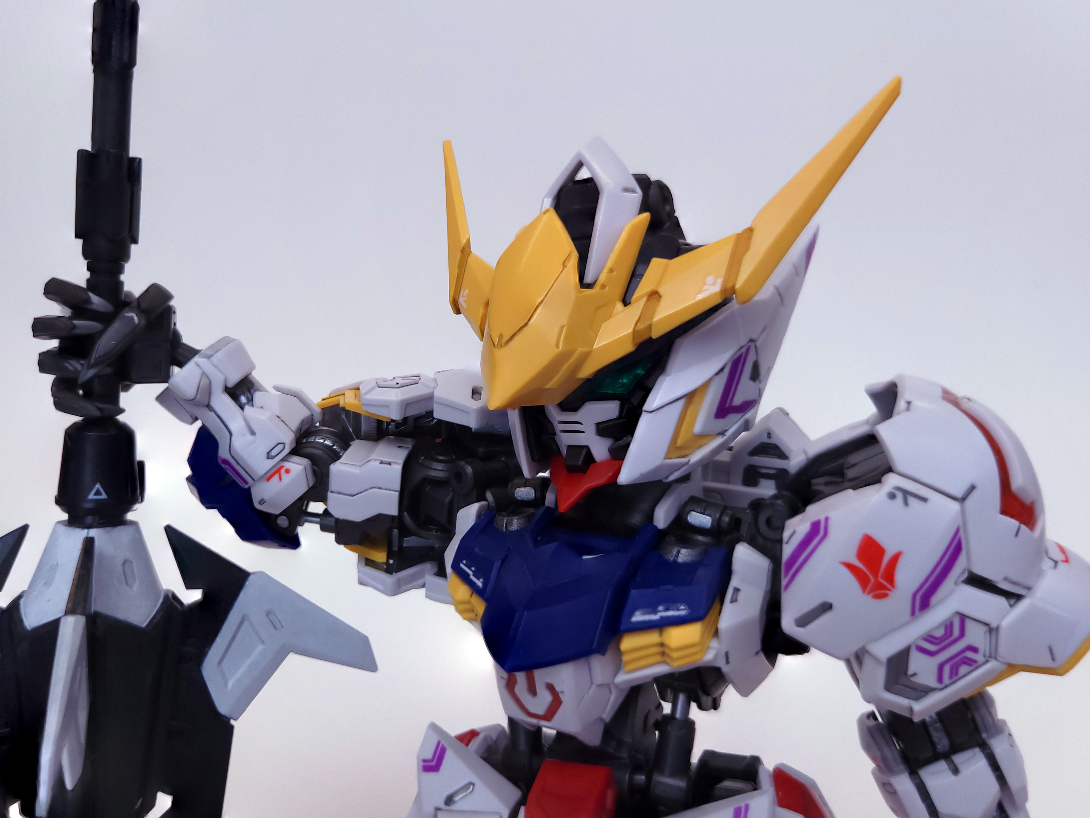 A closeup of Barbatos's head and shoulders. Its mace is planted next to it, on the left side of the frame.