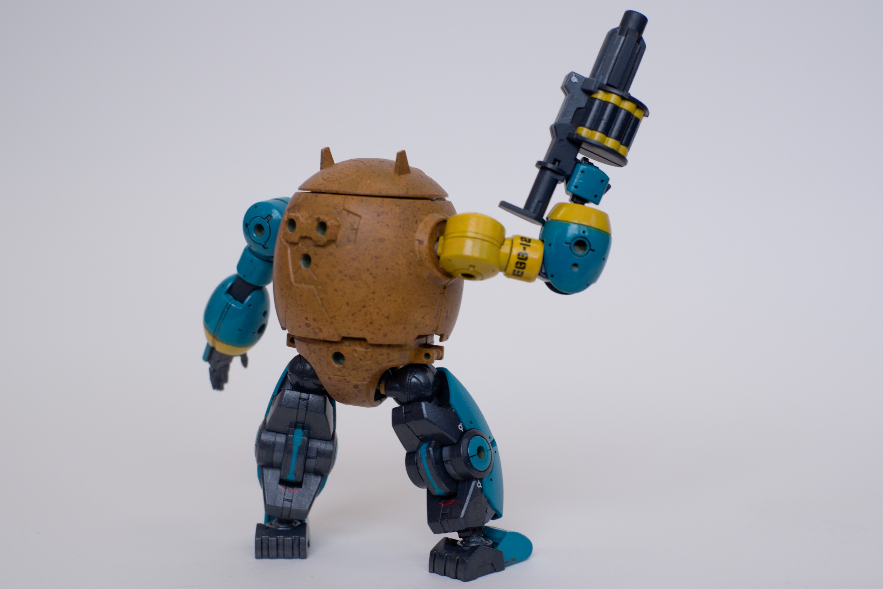 The back side of EGG-12. Its grenade launcher is lifted up in a salute.