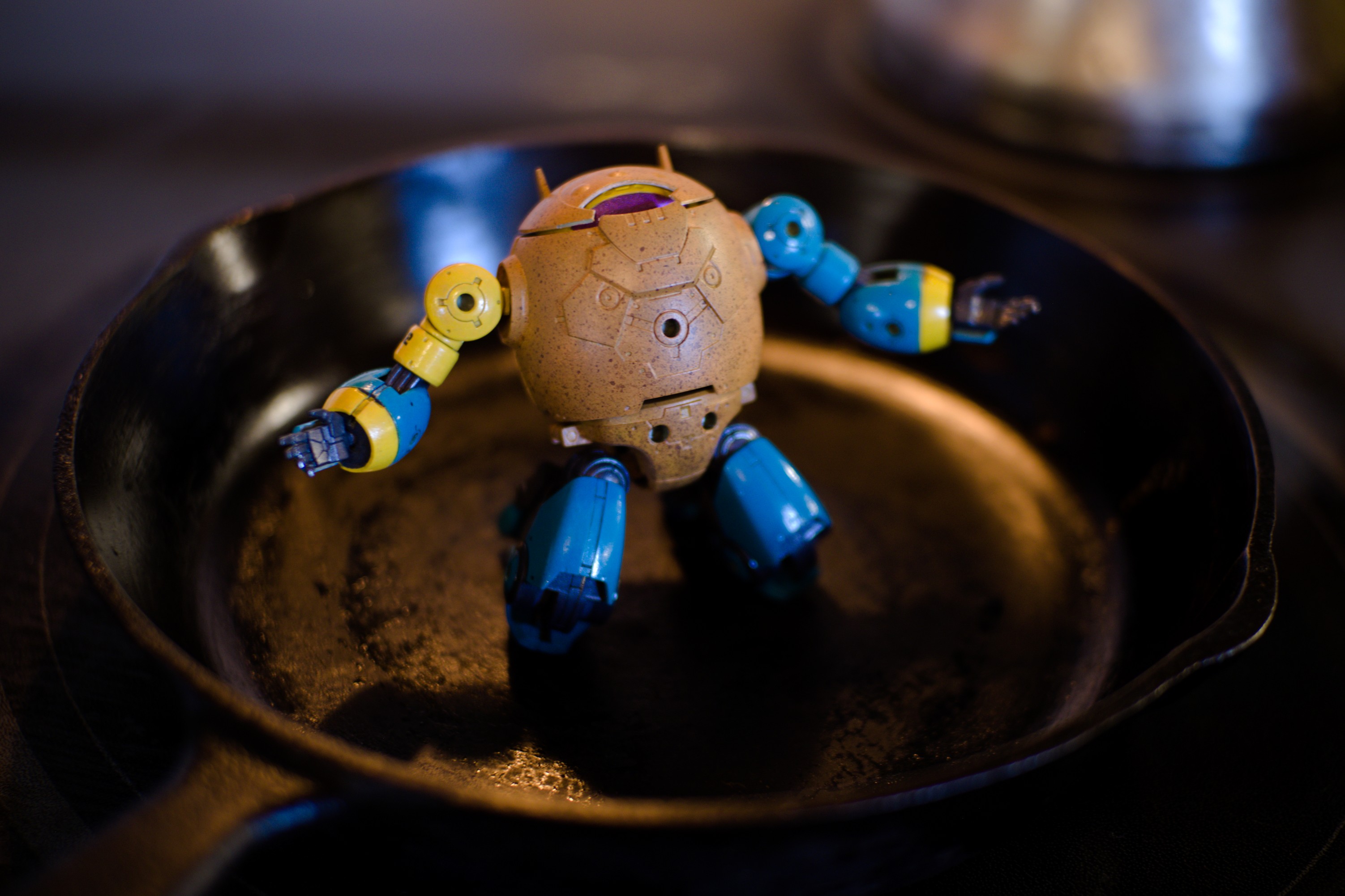 A moodily lit cast iron frying pan holds EGG-12. It is distraught: on its knees, crying out to the heavens in despair