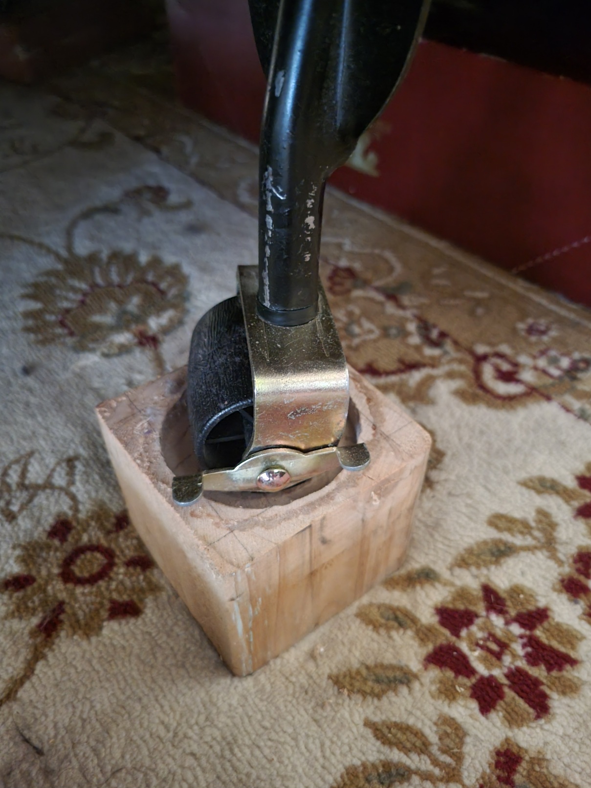A metal bedframe with a fat barrel of a wheel rests inside a circle indent routed out of a chunk of 4x4