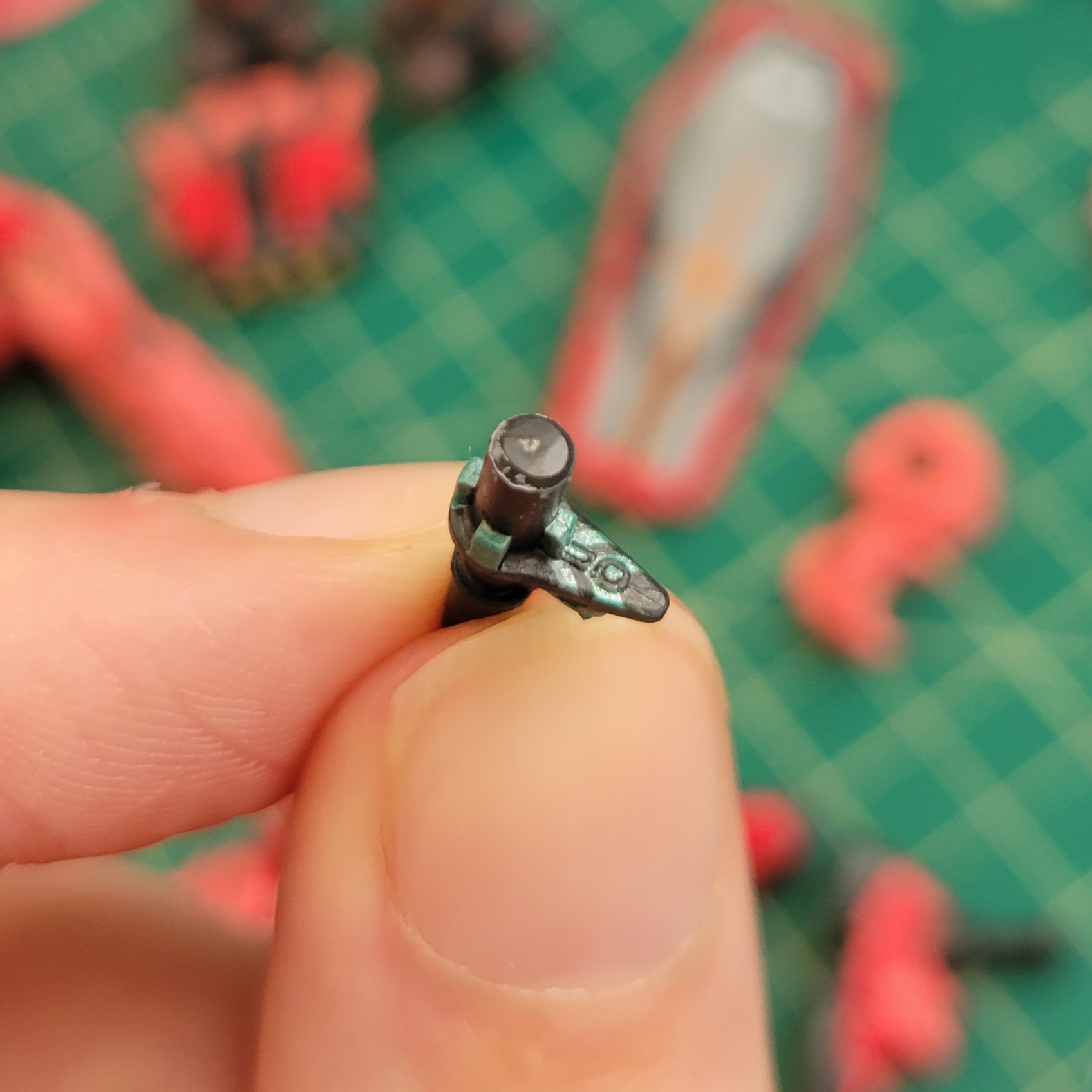 a close up of the top of a bit-mount on the HG GQX Red Gundam. There are shiny green stripes and squares ontop of a flat grey teardrop shape