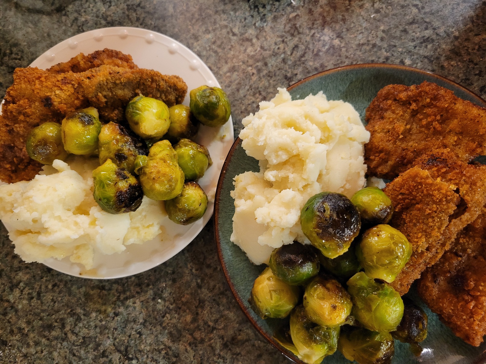 two smallish plates jammed full of country fried steak, mashed potatoes, and brussels sprouts