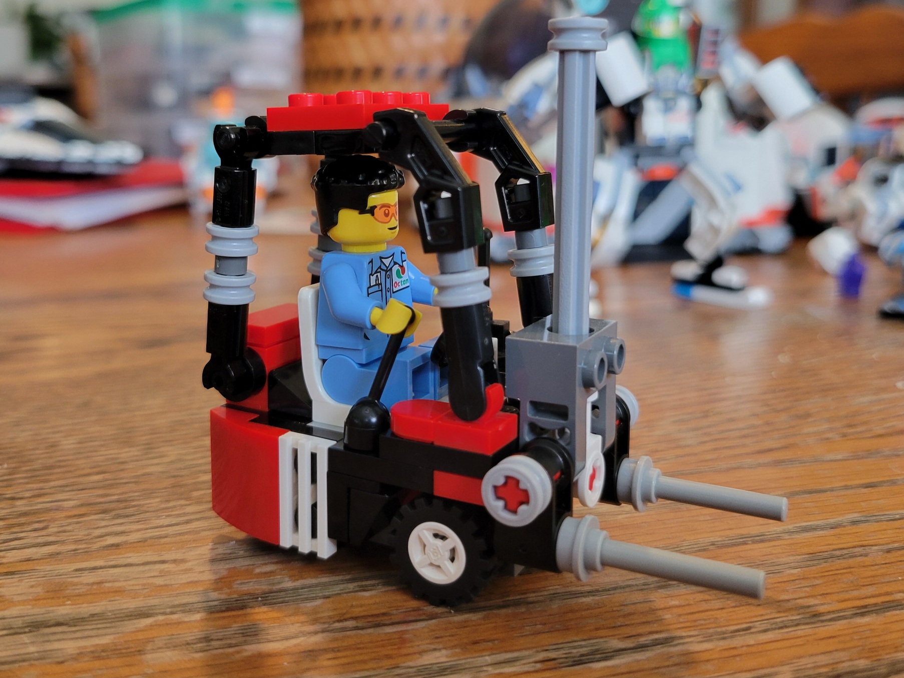 a red, white, and black lego forklift. A lego figure in blue coveralls drives
