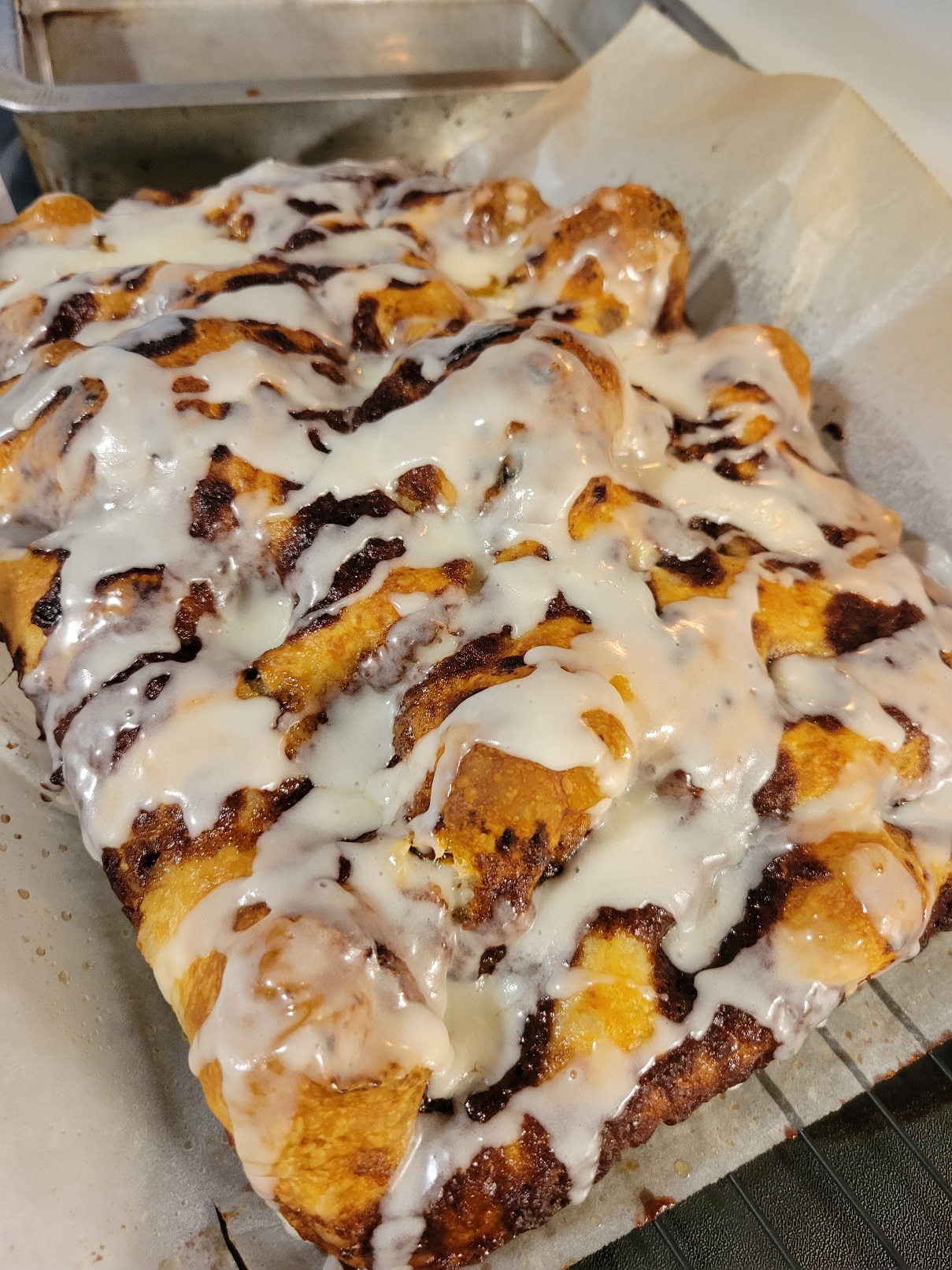 The whole focaccia, golden brown bread mixed with caramelized cinnamon sugar and freshly dizzled with icing