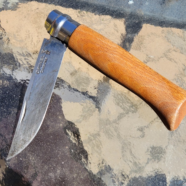 a wooden handled knife with a shining metal ring at the top of the handle