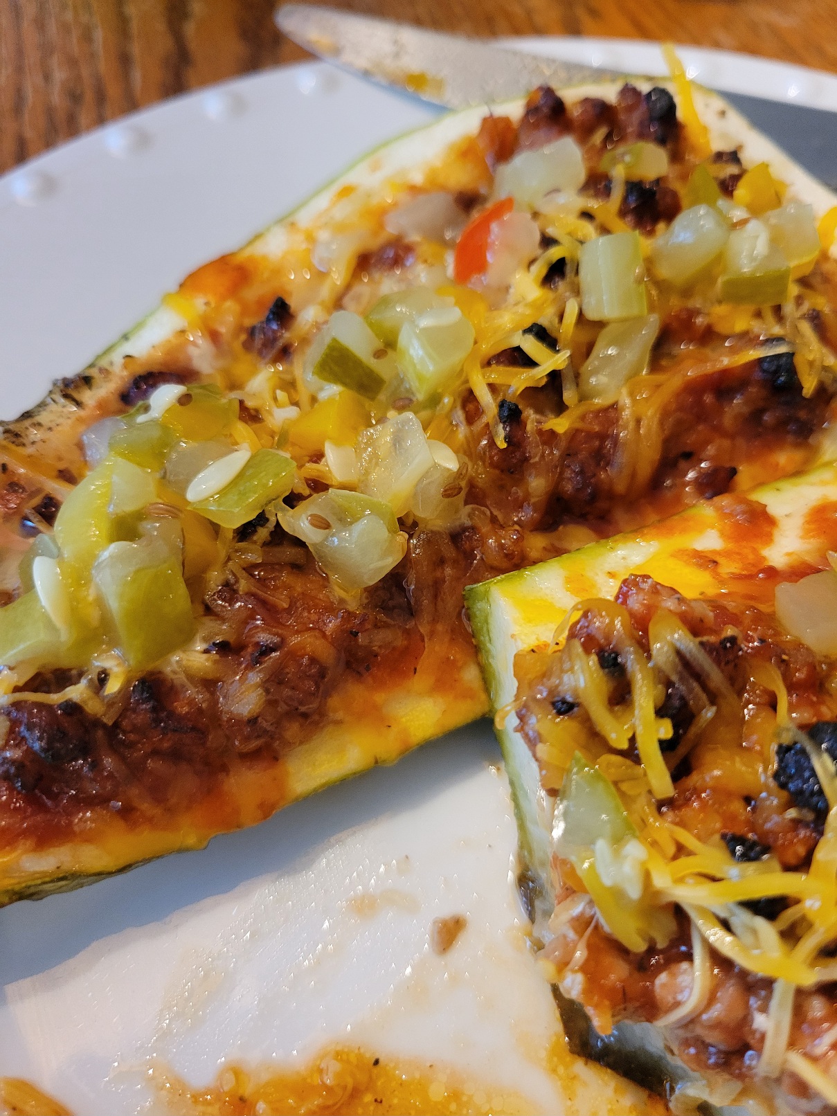 Two zucchini boats stuffed with crisped ground porkland topped with dill relish