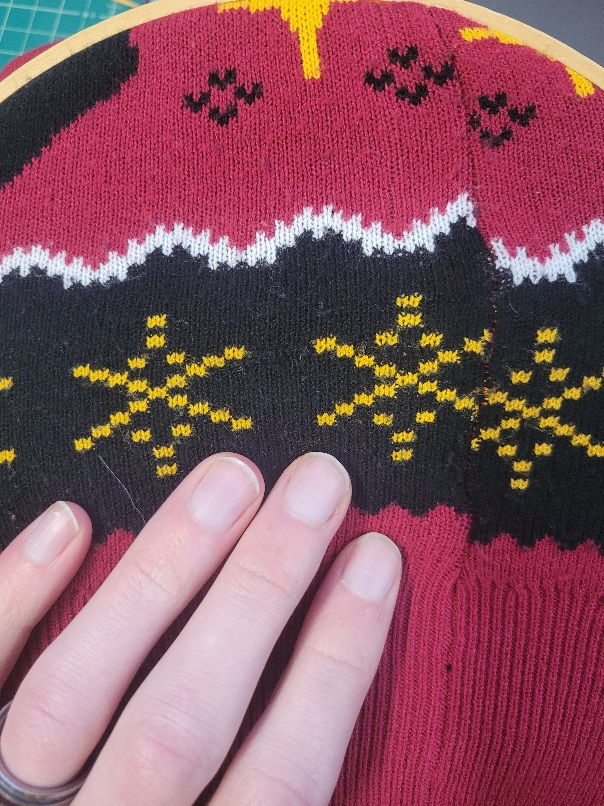 a black, yellow, and red bit of sweater. There is no hole to be seen