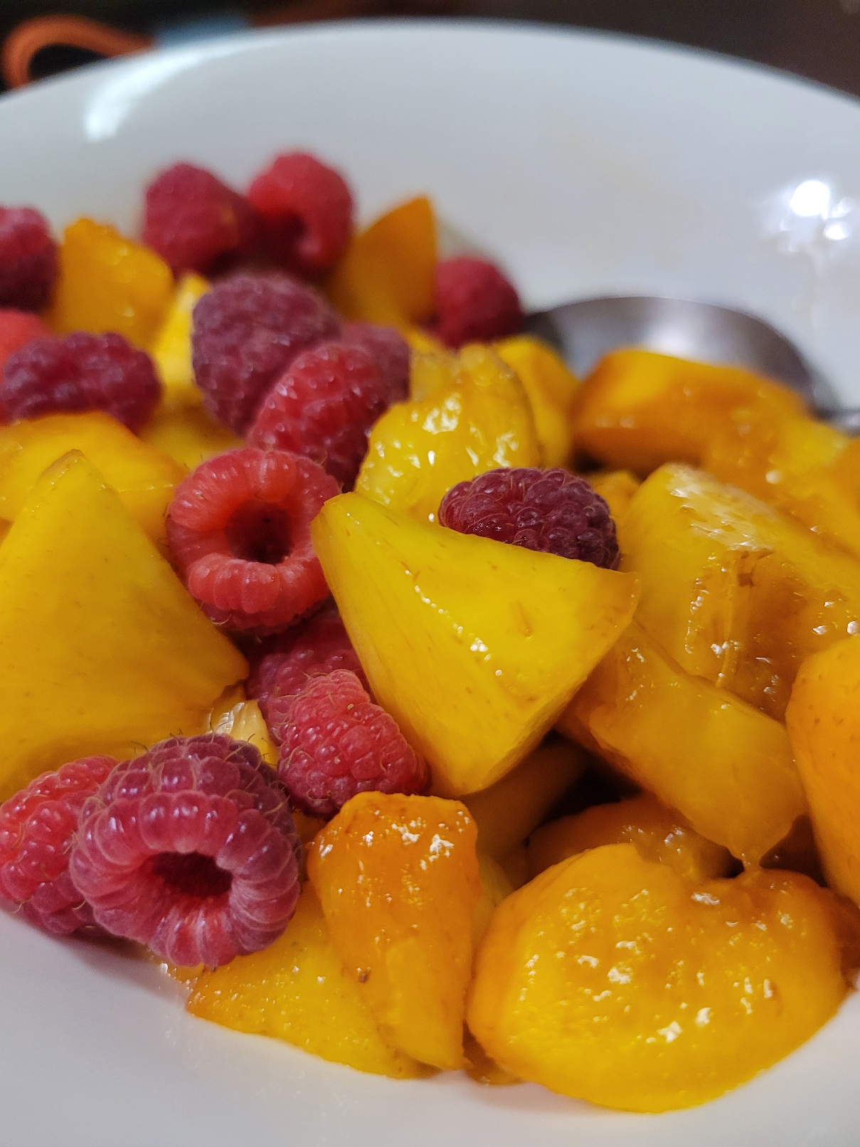 a bowl full of chopped peaches and raspberries