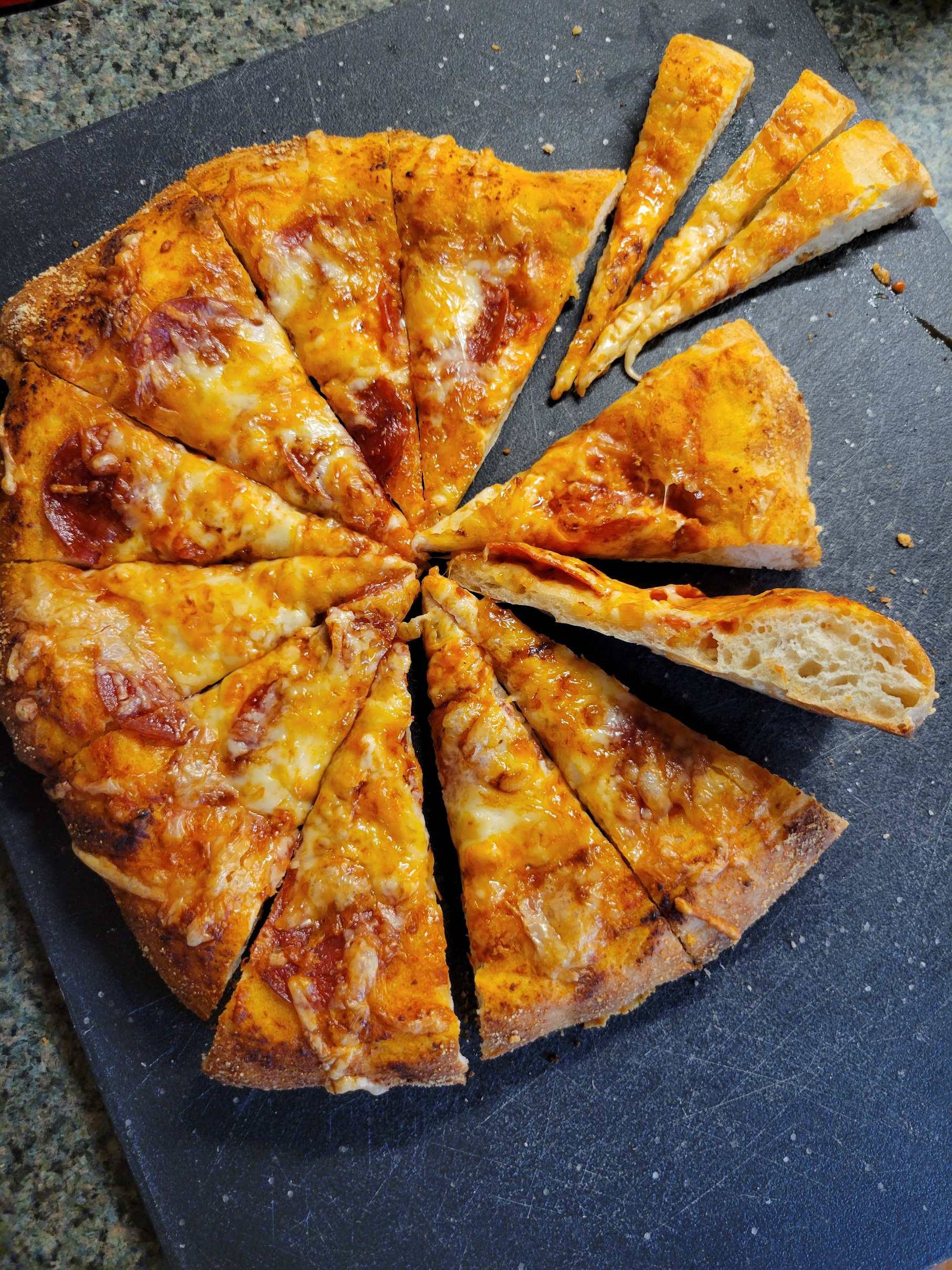 a foofy crusted, well browned pizza with one slice balanced sideways to show the crumb
