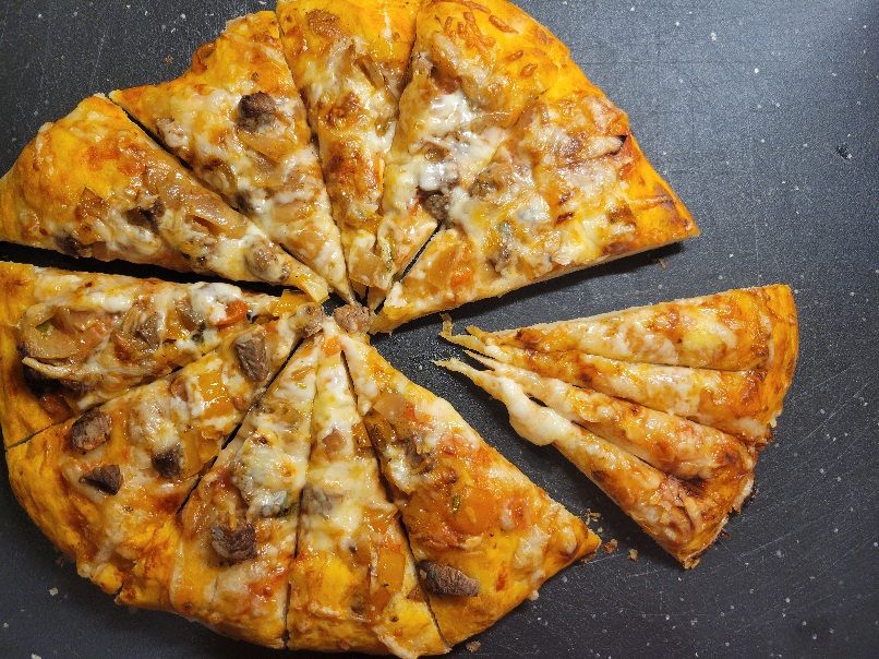 a steak fajita pizza with one slice pulled slightly out from the rest