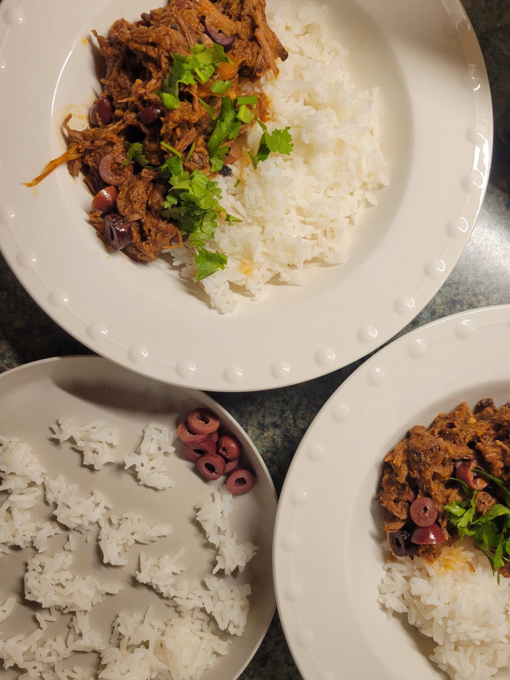 two bowls of ropa vieja and rice and a plate of rice and olives